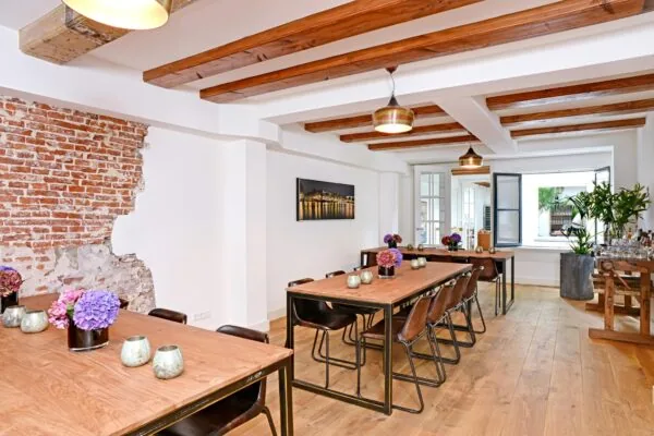 Licht en stijlvol ingericht vergaderruimte aan de Nieuwe Kerkstraat met houten details, bakstenen muuraccent en bloemendecoratie.